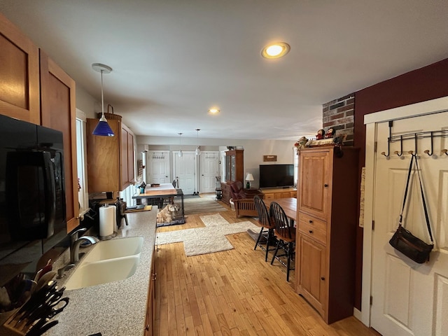 kitchen with sink, decorative light fixtures, and light hardwood / wood-style floors