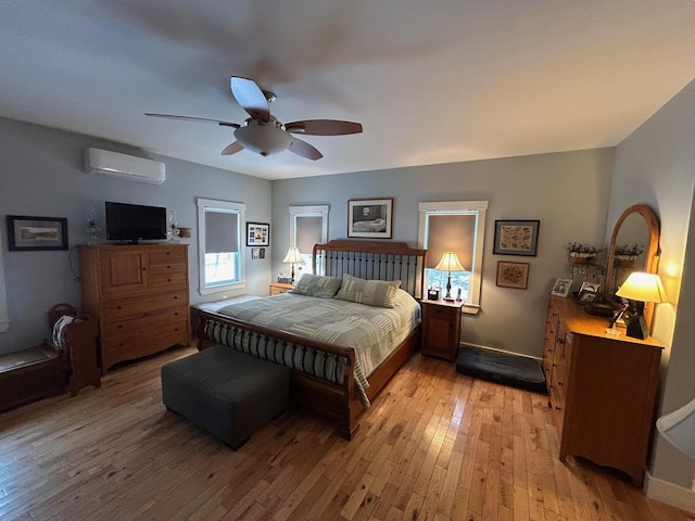 bedroom featuring light hardwood / wood-style flooring, an AC wall unit, and ceiling fan