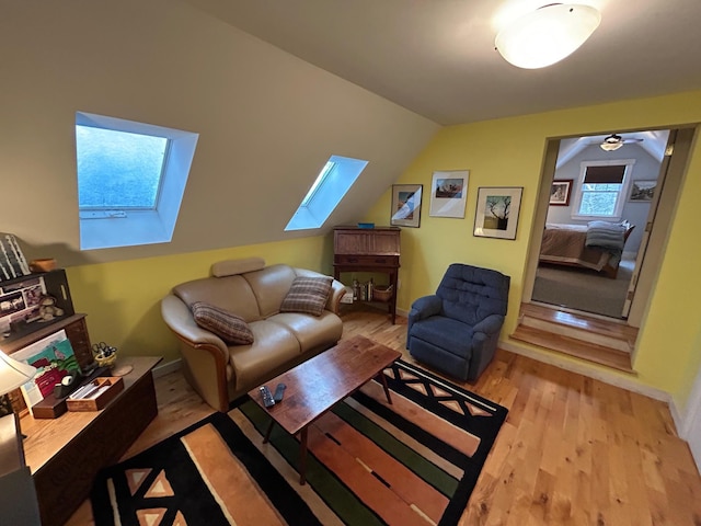 living room with lofted ceiling with skylight and light hardwood / wood-style floors