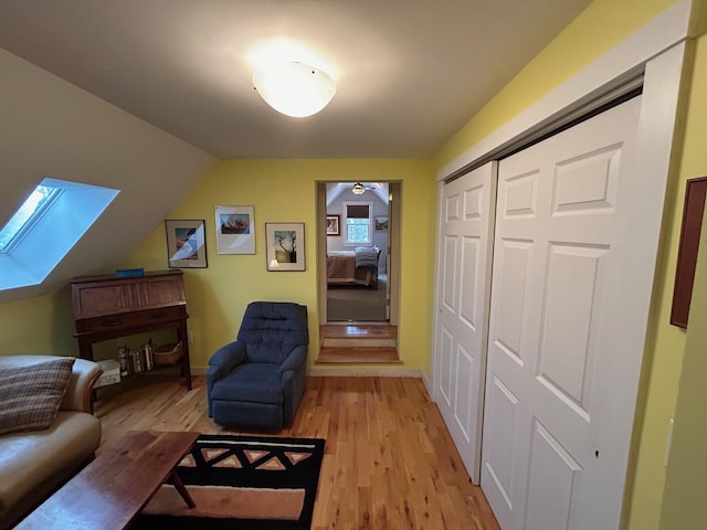 living area with lofted ceiling with skylight and light wood-type flooring