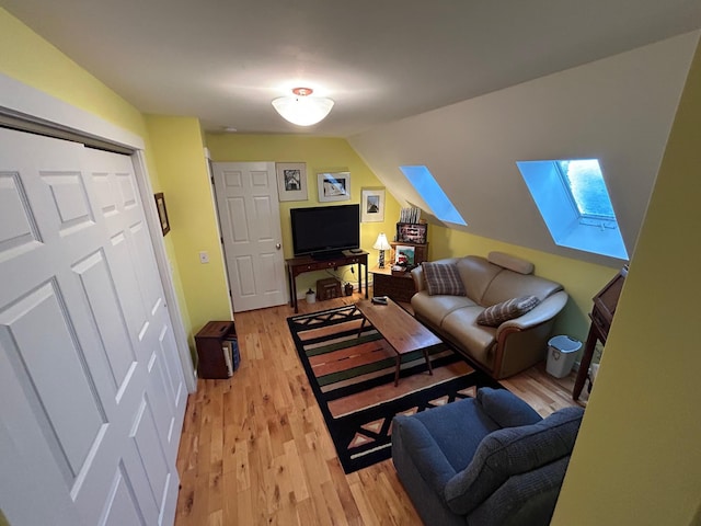 living room with light hardwood / wood-style flooring and lofted ceiling with skylight