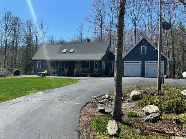 21 Dream Ln, Belfast, ME 04915 - view of front of house featuring a front yard, asphalt driveway, a porch, and a detached garage