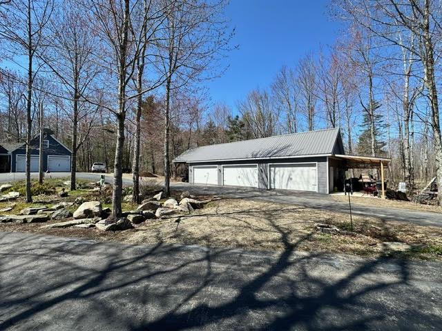 21 Dream Ln, Belfast, ME 04915 - view of home's exterior with a detached garage, an outbuilding, driveway, and metal roof