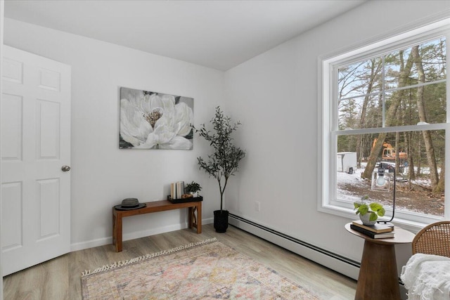 interior space featuring a baseboard heating unit and light hardwood / wood-style flooring