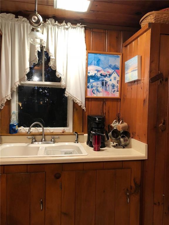 kitchen with wood walls, sink, and wooden ceiling