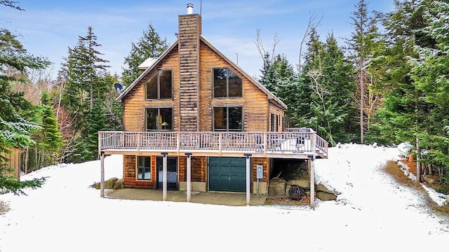 snow covered property featuring a wooden deck and a garage