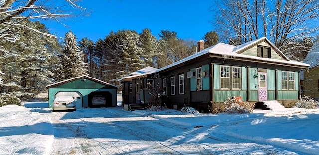 view of snow covered exterior featuring a garage and an outdoor structure