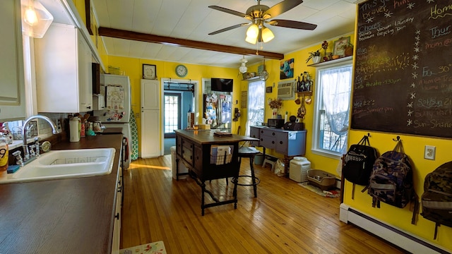 kitchen with beamed ceiling, a healthy amount of sunlight, a baseboard heating unit, and sink