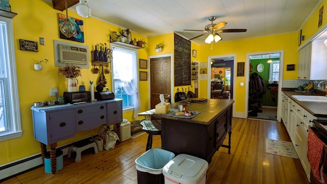 kitchen with hardwood / wood-style flooring, white cabinetry, sink, and a wall mounted air conditioner