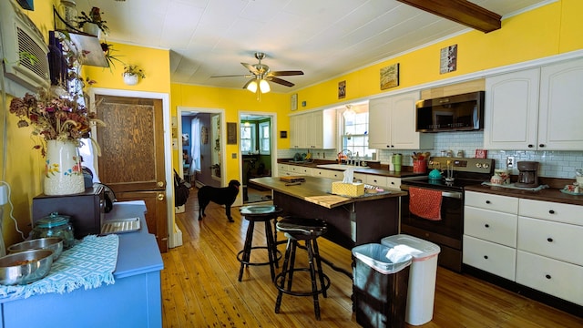 kitchen featuring sink, wood-type flooring, white cabinets, stainless steel electric range oven, and decorative backsplash