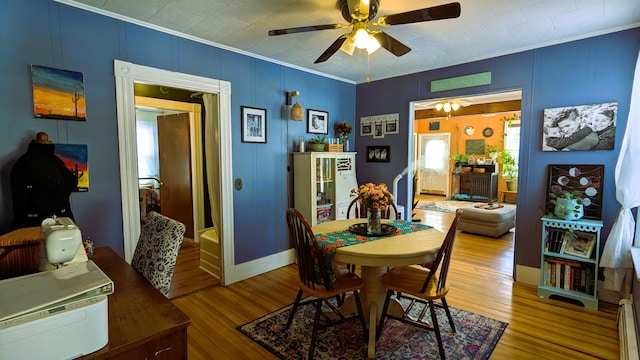 dining room featuring hardwood / wood-style floors, crown molding, ceiling fan, and baseboard heating