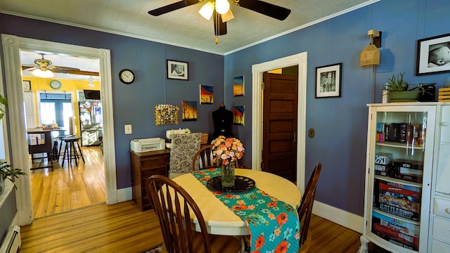 dining space featuring hardwood / wood-style flooring, ceiling fan, ornamental molding, and baseboard heating