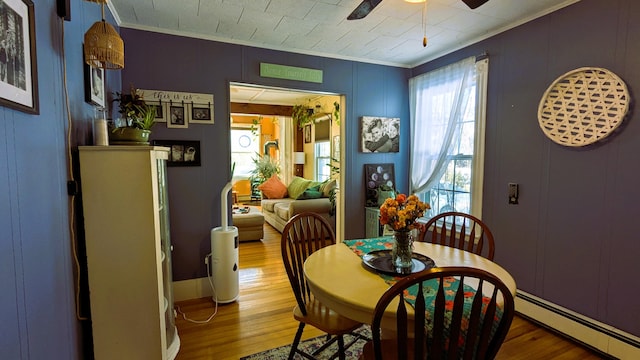 dining area with crown molding, a wealth of natural light, baseboard heating, and hardwood / wood-style flooring