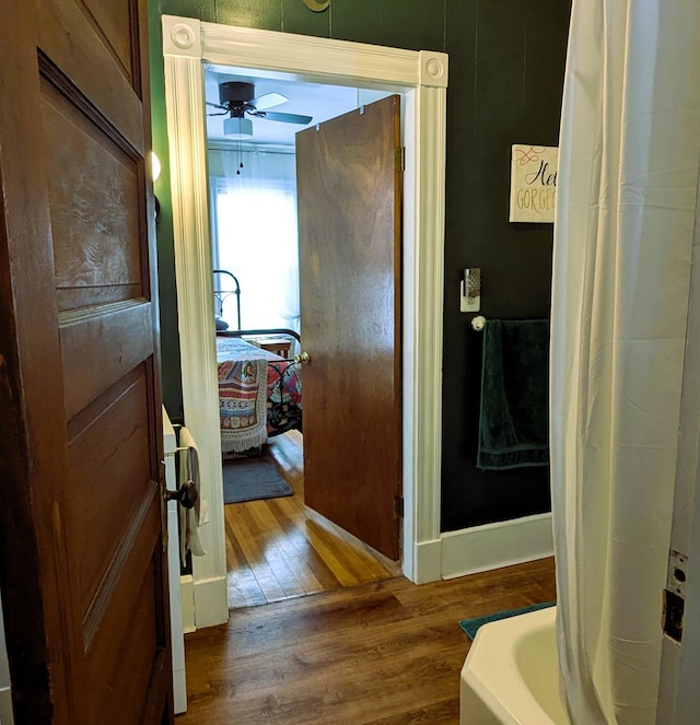 bathroom with hardwood / wood-style flooring, a washtub, and ceiling fan