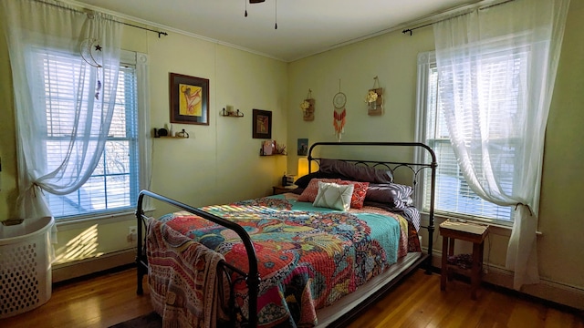 bedroom with hardwood / wood-style flooring, ornamental molding, and a baseboard heating unit