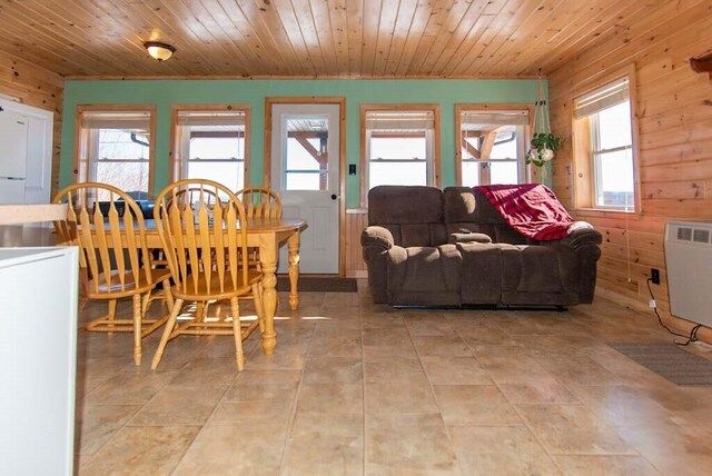 tiled dining room with heating unit, wooden walls, and wooden ceiling