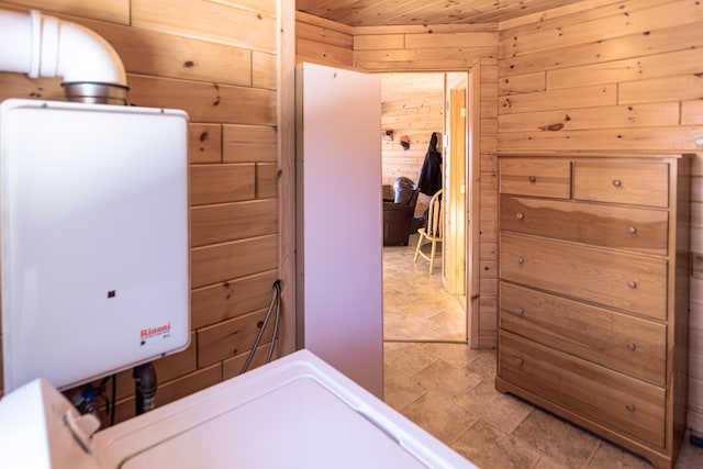 clothes washing area featuring wood ceiling, water heater, and wood walls