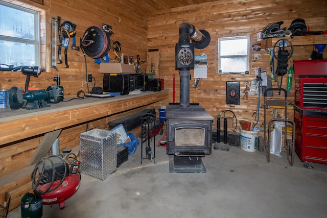 misc room with a wood stove, concrete floors, and wood walls