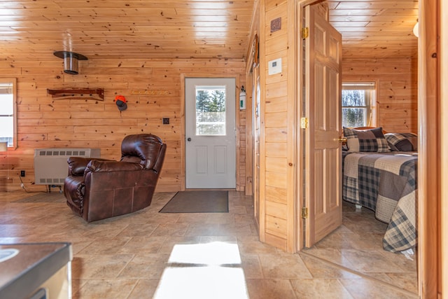 foyer featuring vaulted ceiling, plenty of natural light, wood ceiling, and wooden walls