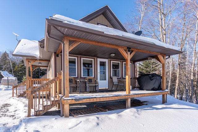 snow covered deck featuring a porch and a grill