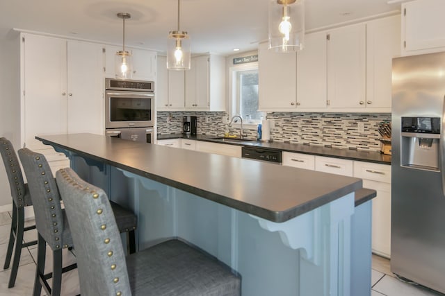 kitchen with appliances with stainless steel finishes, white cabinetry, sink, a kitchen bar, and hanging light fixtures