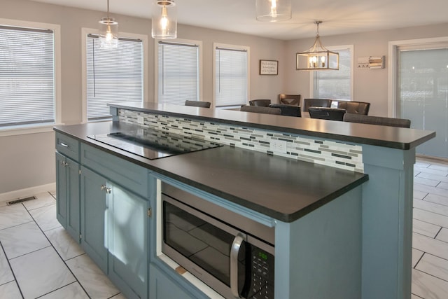 kitchen featuring black electric cooktop, decorative light fixtures, blue cabinetry, and a kitchen island