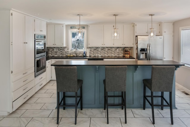 kitchen with appliances with stainless steel finishes, hanging light fixtures, and white cabinets