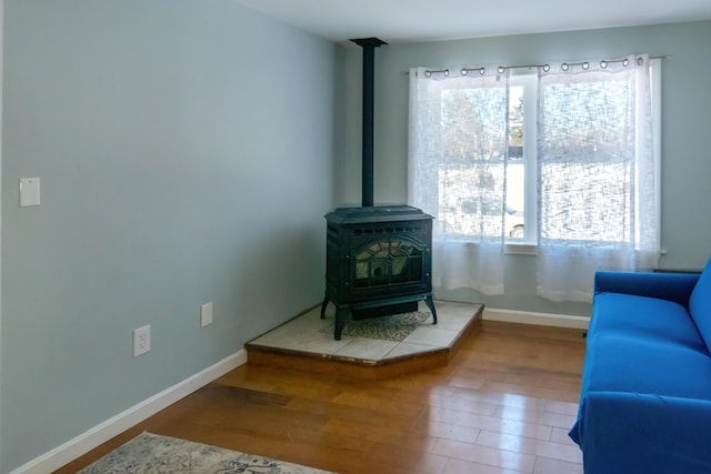 living area with a healthy amount of sunlight, wood-type flooring, and a wood stove