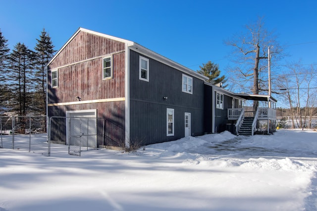 snow covered back of property featuring a garage