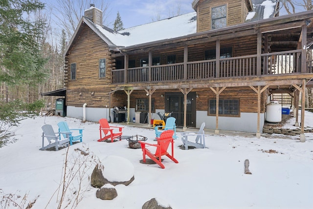 snow covered back of property featuring a fire pit