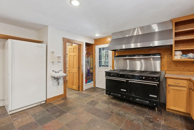 kitchen with range with two ovens, extractor fan, white fridge, and sink