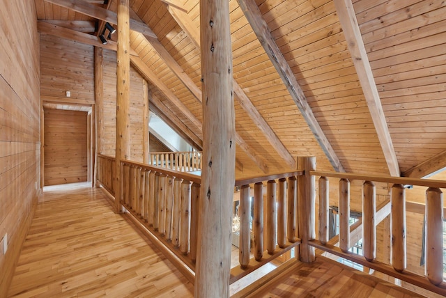 corridor featuring beam ceiling, wooden ceiling, wooden walls, and light hardwood / wood-style flooring