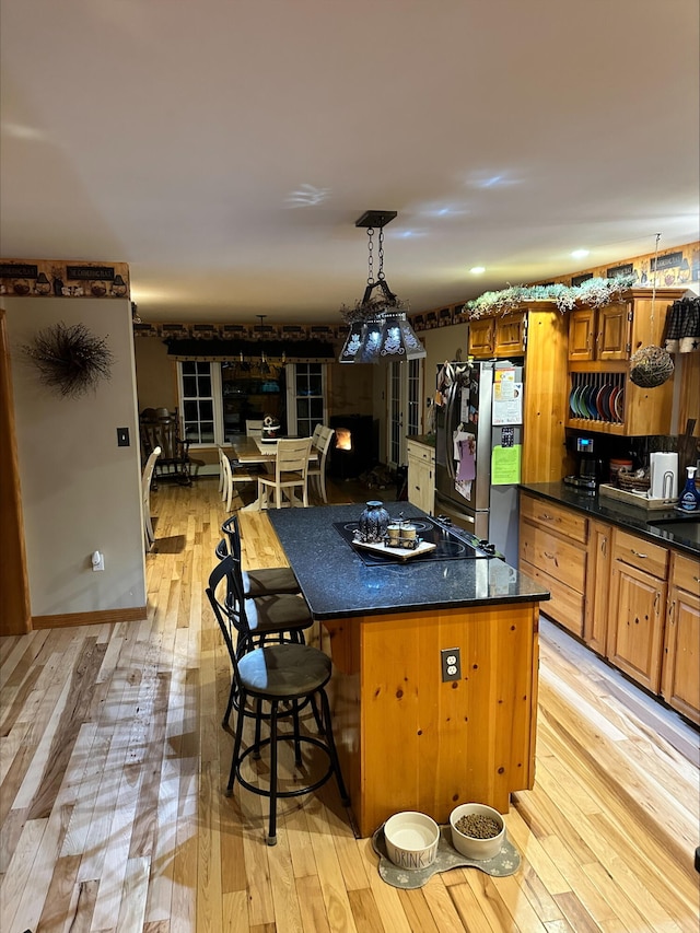 kitchen featuring pendant lighting, stainless steel fridge, a kitchen breakfast bar, light hardwood / wood-style floors, and a kitchen island