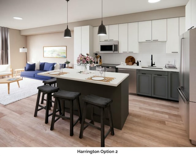 kitchen featuring a breakfast bar, stainless steel appliances, tasteful backsplash, light countertops, and a sink