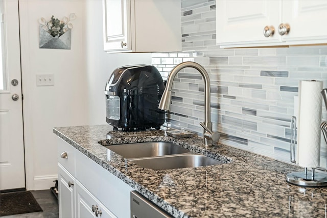 kitchen featuring tasteful backsplash, sink, white cabinets, dark stone counters, and stainless steel dishwasher