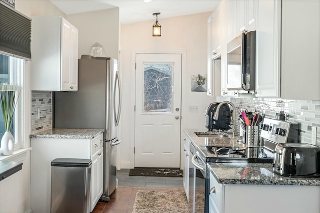 kitchen featuring appliances with stainless steel finishes, decorative light fixtures, white cabinetry, sink, and dark stone countertops