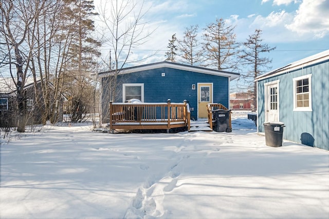 snow covered rear of property with a wooden deck