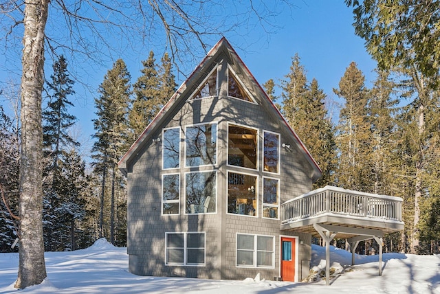 snow covered back of property with a deck