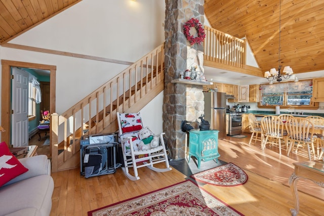 living room featuring a wood stove, a chandelier, wood ceiling, and light wood-type flooring