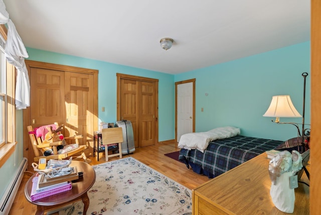 bedroom featuring baseboard heating and hardwood / wood-style flooring