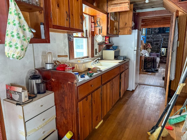 kitchen with sink, tile walls, tasteful backsplash, light wood-type flooring, and white fridge