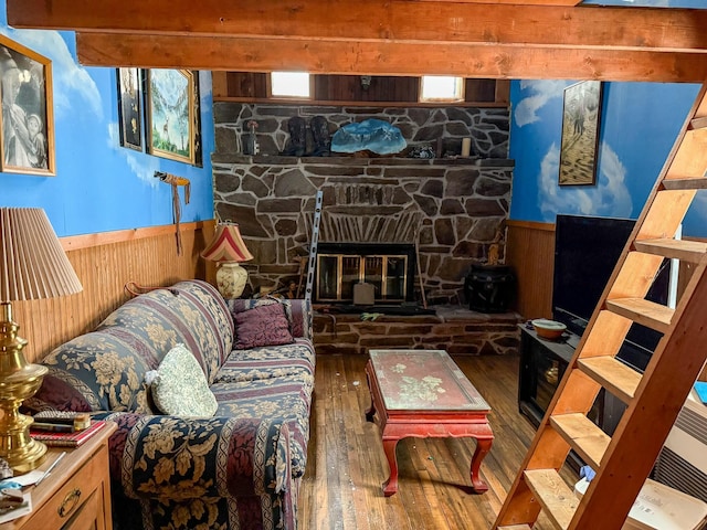 living room with a stone fireplace, dark wood-type flooring, and wooden walls