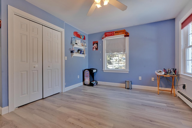 unfurnished bedroom with light wood finished floors, a closet, baseboard heating, and baseboards