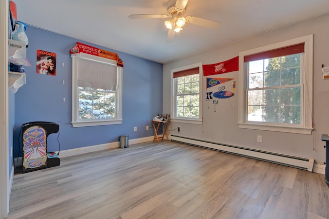 empty room featuring a ceiling fan, baseboards, wood finished floors, and a baseboard radiator