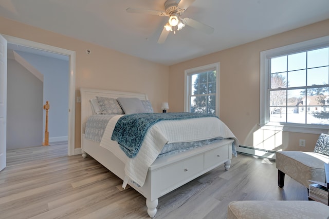 bedroom featuring a ceiling fan, baseboard heating, and light wood-style floors