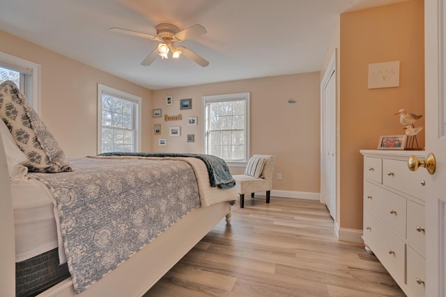 bedroom with a closet, ceiling fan, light wood-style flooring, and baseboards