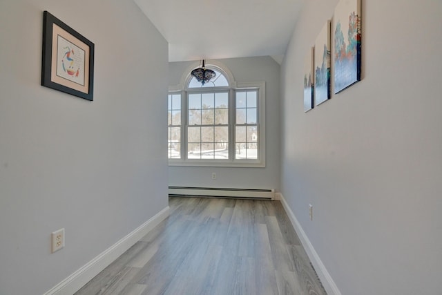 interior space featuring a notable chandelier, baseboard heating, wood finished floors, and baseboards