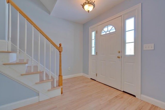 entryway with baseboards, wood finished floors, and stairs