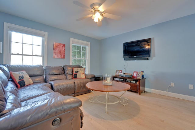 living room featuring a ceiling fan, baseboards, and light wood-type flooring