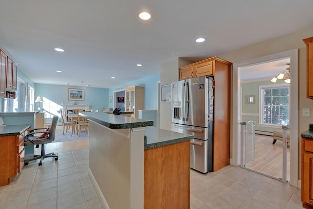 kitchen with light tile patterned floors, a center island, stainless steel refrigerator with ice dispenser, and a healthy amount of sunlight